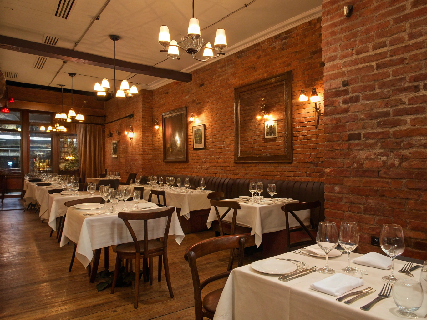 Warmly lit boutique restaurant dining room with plated dinner dishes and wine glasses
